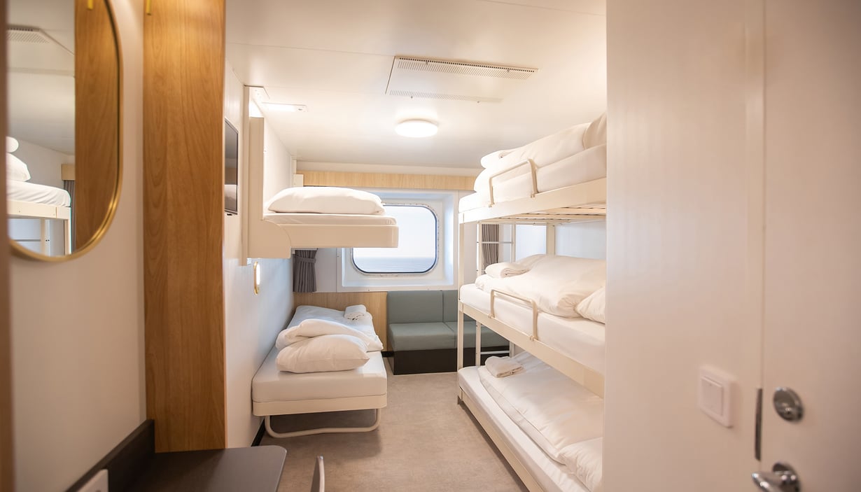 Cabin with two sets of bunk beds, window, and seating area.