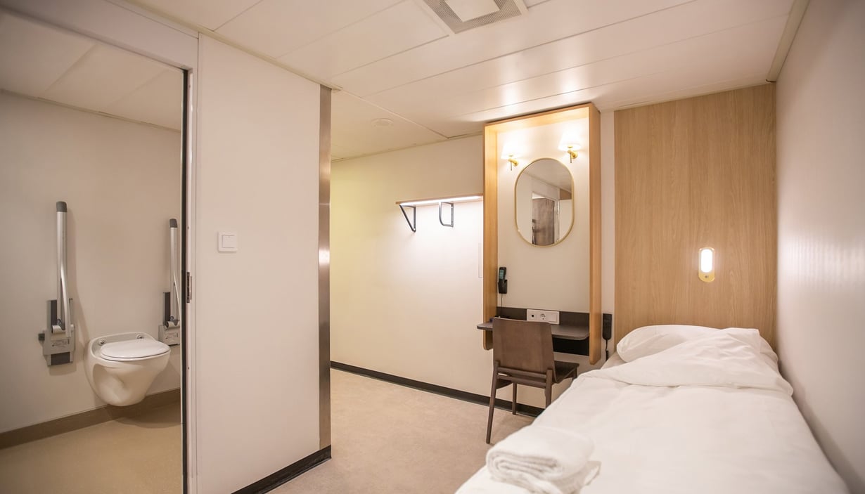 Accessible cabin with a bed, desk, and bathroom.