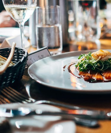 Dining table with gourmet dish, wine glasses, and breadsticks at a formal restaurant setting.