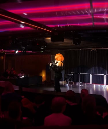 Performer with curly wig on stage.