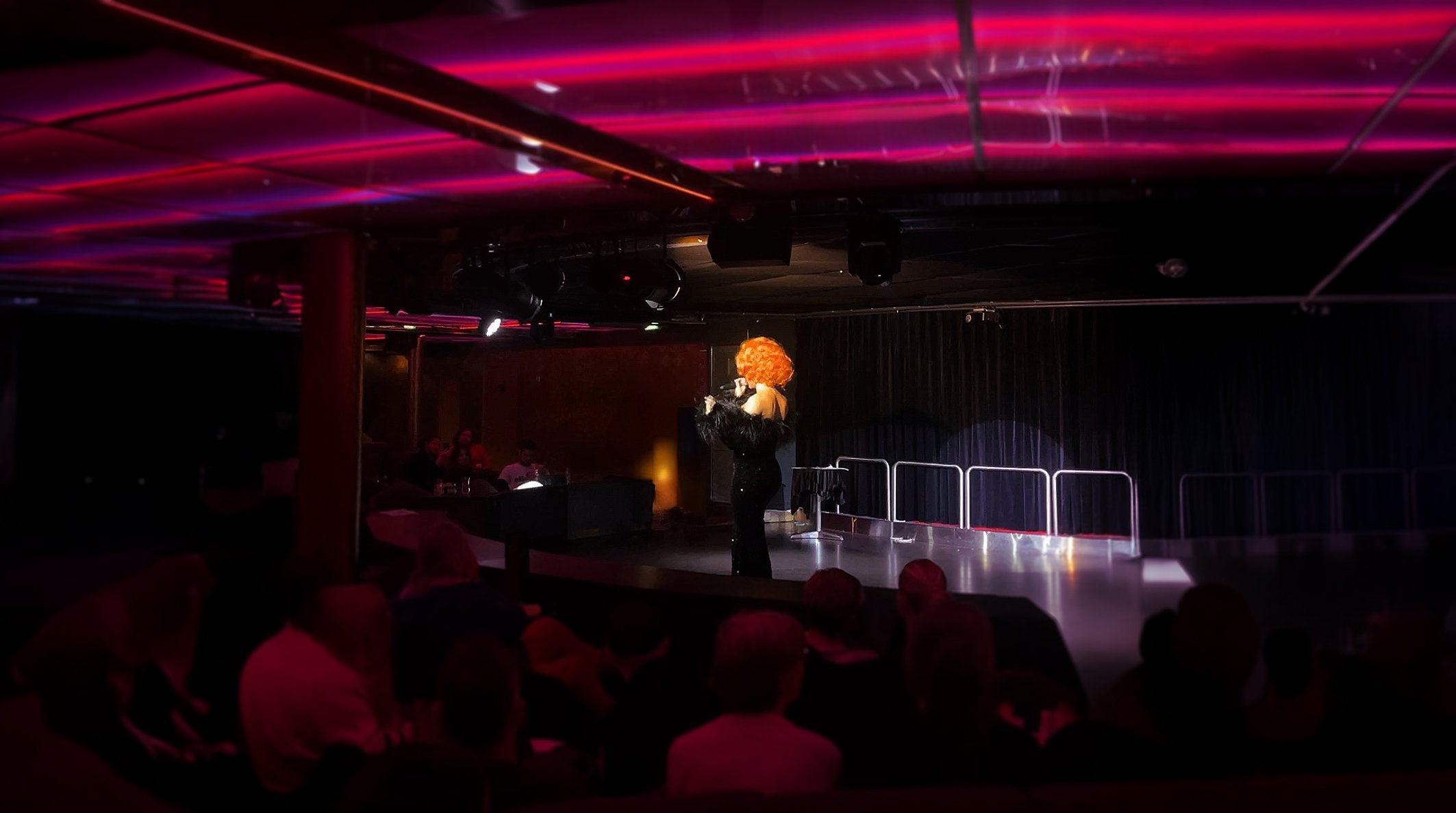 Performer with curly wig on stage.
