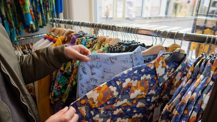 Person browsing shirts in a clothing store in Oslo.