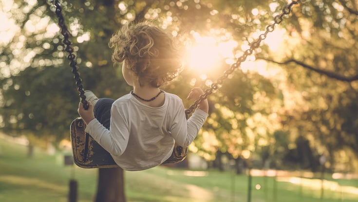 Child on a swing in a sunny park near Oslo.