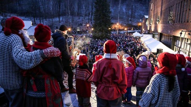 Festive crowd in Oslo with stage and Christmas tree.
