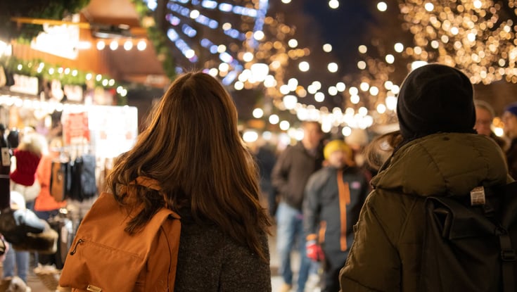 Two people walking through a lit-up market in Oslo.