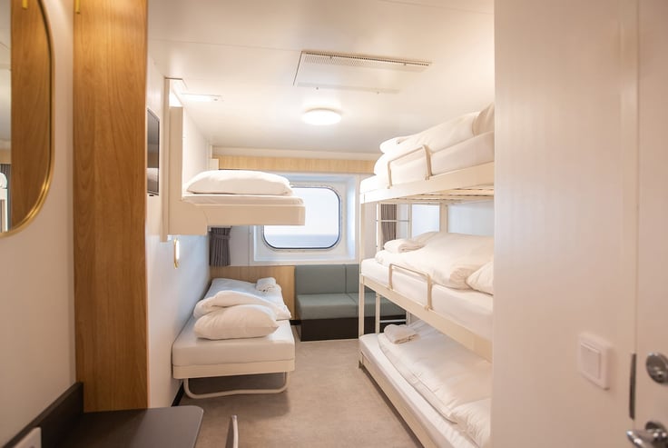 Cabin with two sets of bunk beds, window, and seating area.