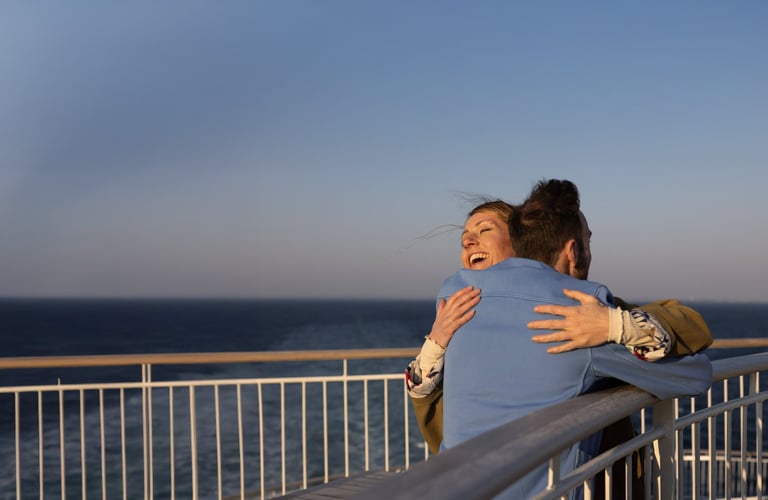 Two people embracing on a balcony overlooking the sea.