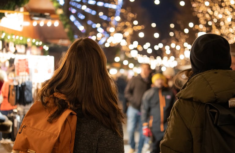 Two people walking through a lit-up market in Oslo.