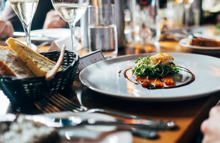 Dining table with gourmet dish, wine glasses, and breadsticks at a formal restaurant setting.